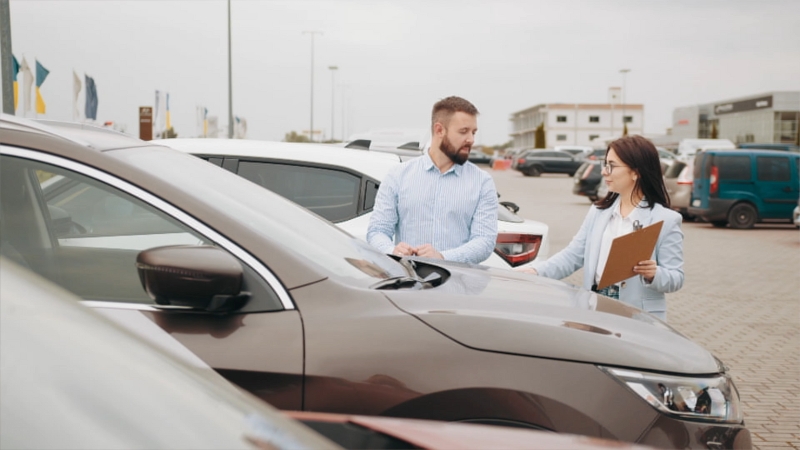 A Car Buyer and A Salesperson Discussing Options at A Used Car Dealership