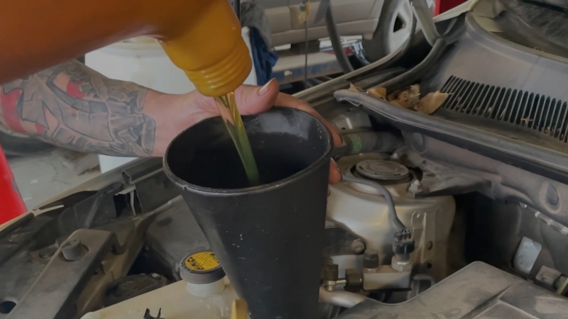 Pouring Oil Into a Funnel During a Car’s Oil Change