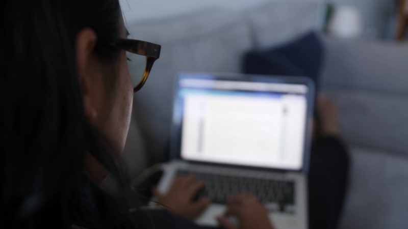 A Person Researching on A Laptop While Sitting on A Couch