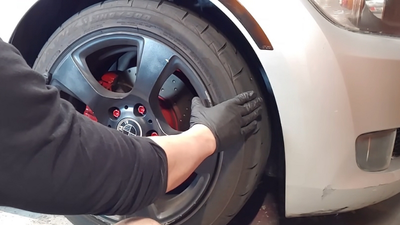 A Mechanic Inspecting the Tire of A Used Car