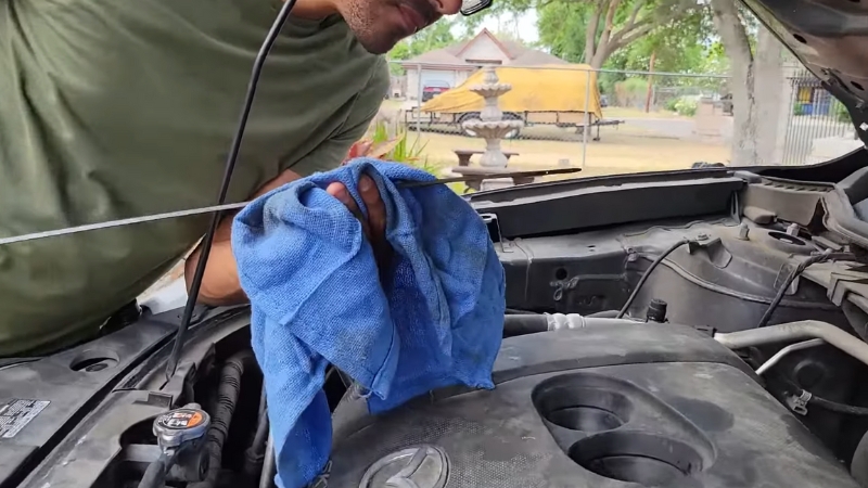 A Person Checking the Oil Level in A Car Engine with A Cloth in Hand