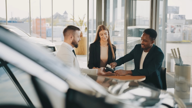 A Customer Discussing Terms and Making a Payment at A Car Dealership While Buying a Used Car