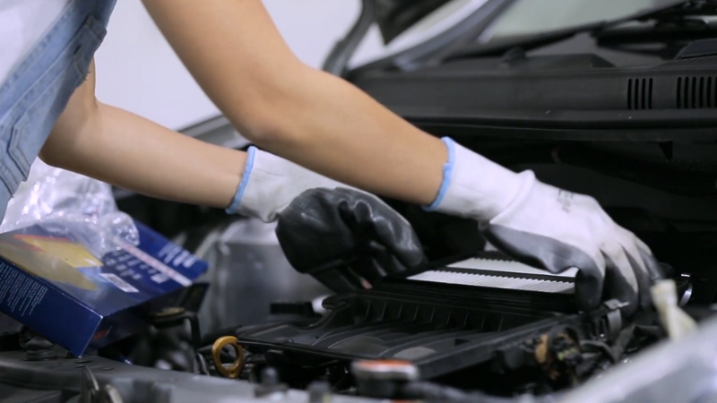 A Person Replacing the Car's Air Filter Under the Hood of A Vehicle