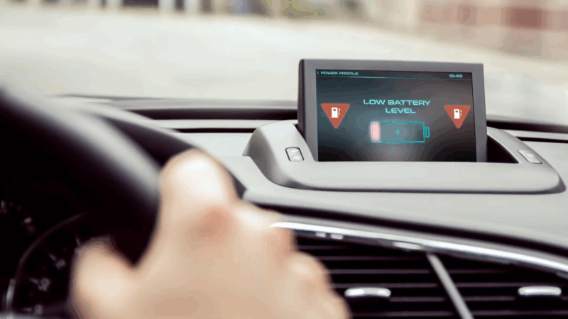 A dashboard screen in a car showing a "Low Battery Level" warning with an icon indicating battery depletion