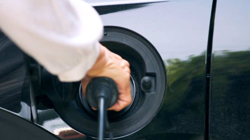 Person plugging in an electric vehicle to charge