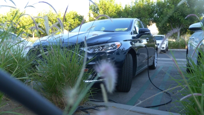An electric vehicle charging in a parking lot, symbolizing the future of EV ownership incentives