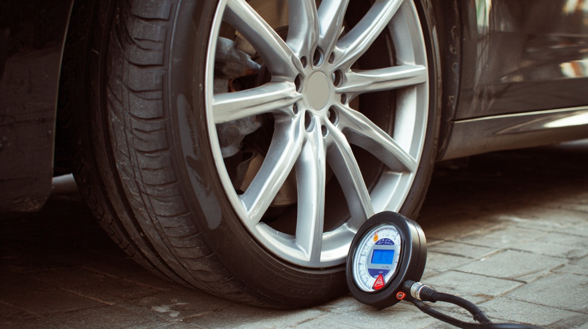 Close-up of a car tire with a digital tire pressure gauge attached