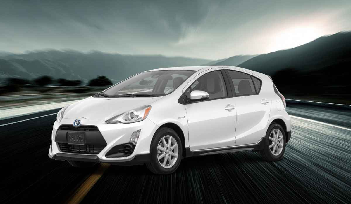 White Toyota Prius c One driving on a highway with blurred mountains in the background