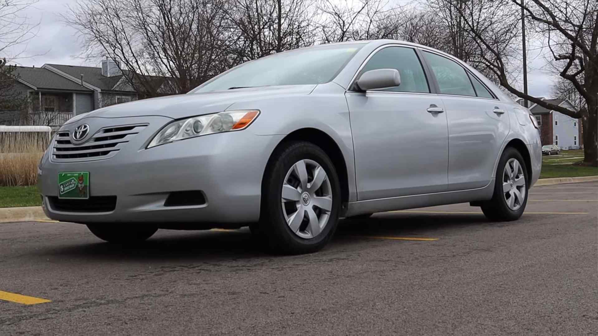 Silver Toyota Camry parked in a residential parking lot with bare trees