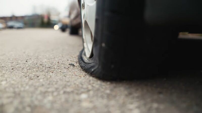 Car tire with very low pressure visibly flattened against the road surface