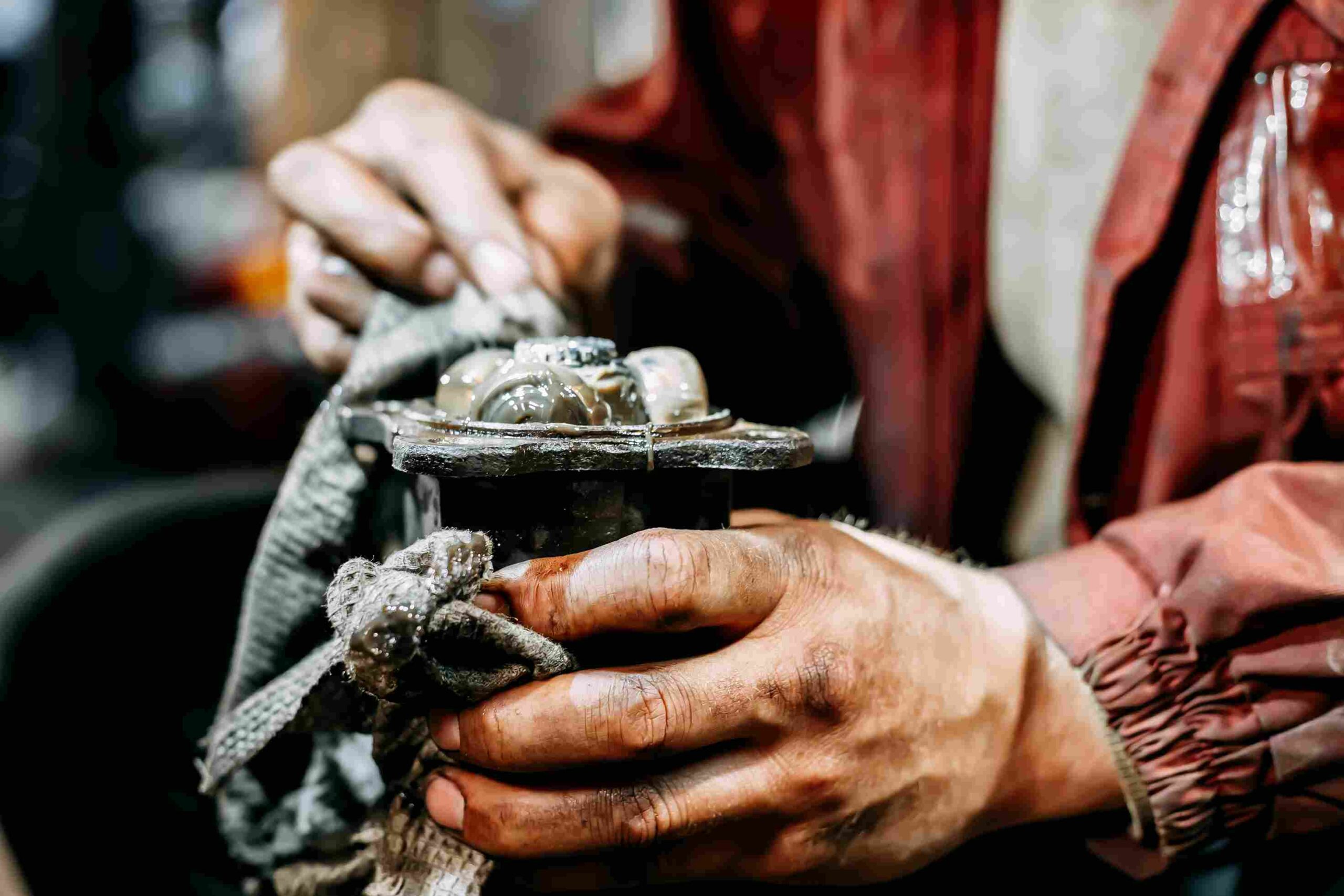 Hands wiping grease from a CV joint part with a cloth