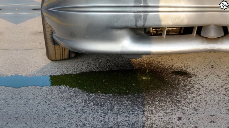 Coolant leak under a car with green fluid pooling near the front bumper