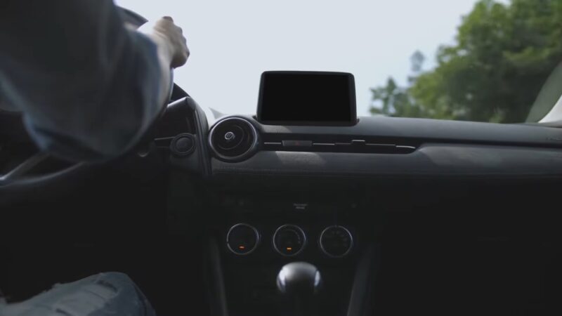 Driver inside a car holding the steering wheel while driving on the road