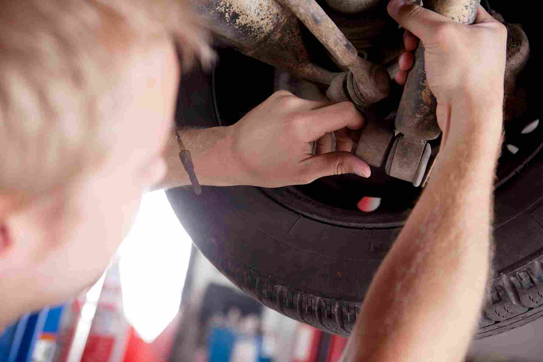 Mechanic checking car suspension parts near the wheel and axle