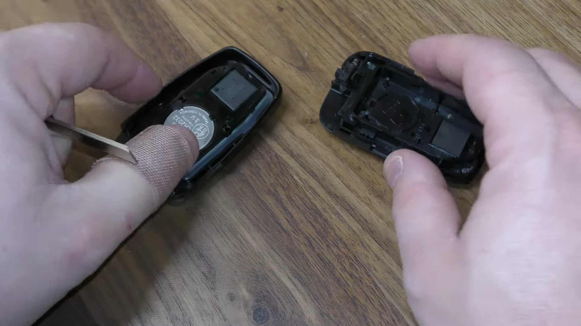 Hands opening a Prius smart key fob case to reveal the internal battery