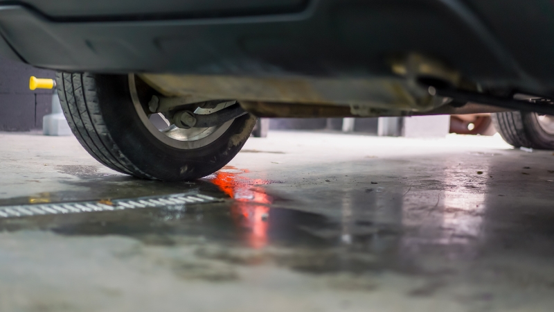 Coolant leaking under a car near the front wheel on a garage floor