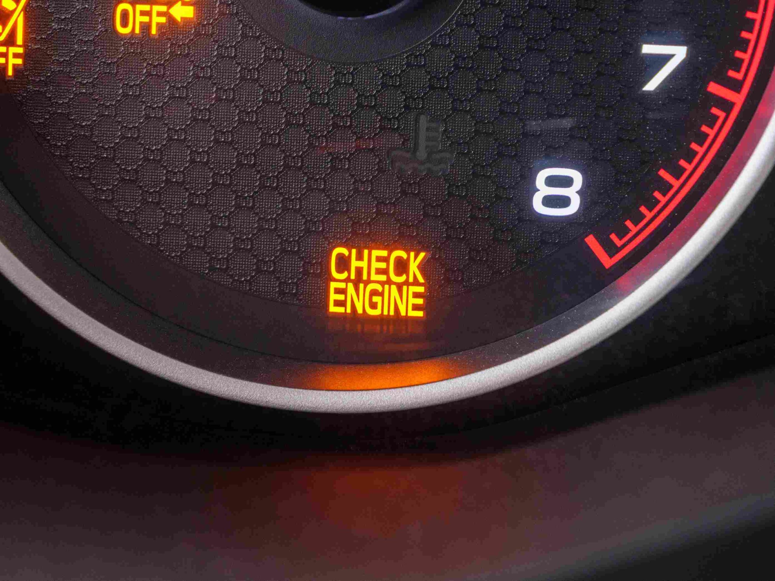 A car dashboard displaying a glowing check engine light