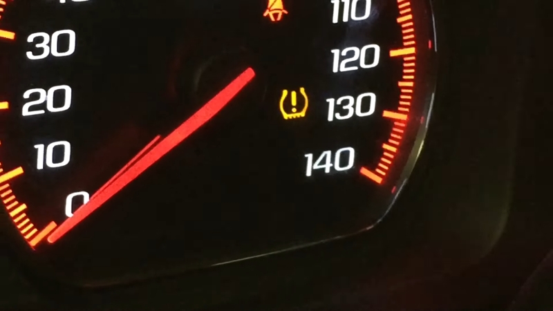 Tire pressure light on dashboard with speedometer showing warning that may require professional inspection