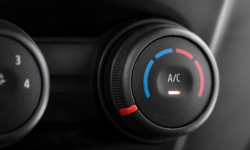 Close-up of a car's air conditioning dial, with blue and red segments indicating temperature