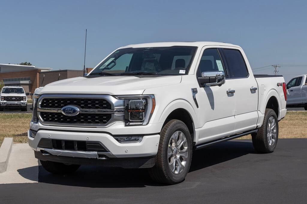 White Ford F-150 parked outdoors showing front and side profile on dealership lot